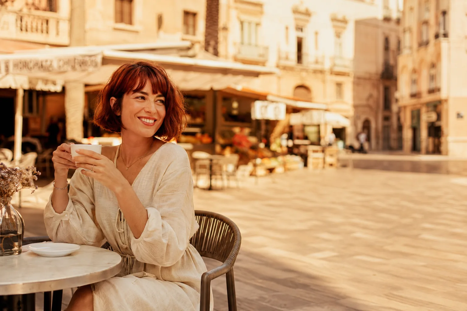 Mujer sonriente tomando un café en una terraza de Valencia